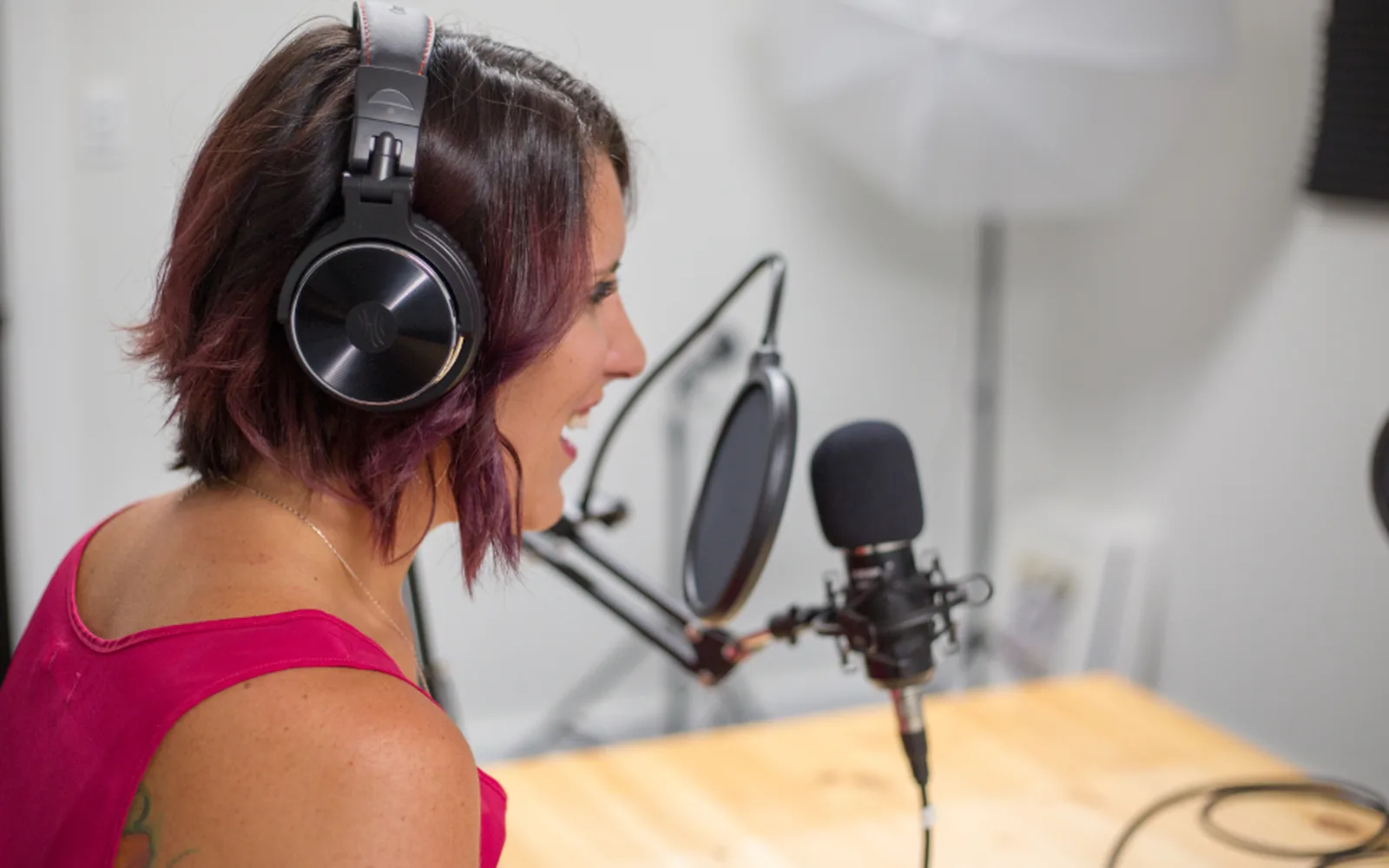 A podcaster in headphones laughing at the microphone