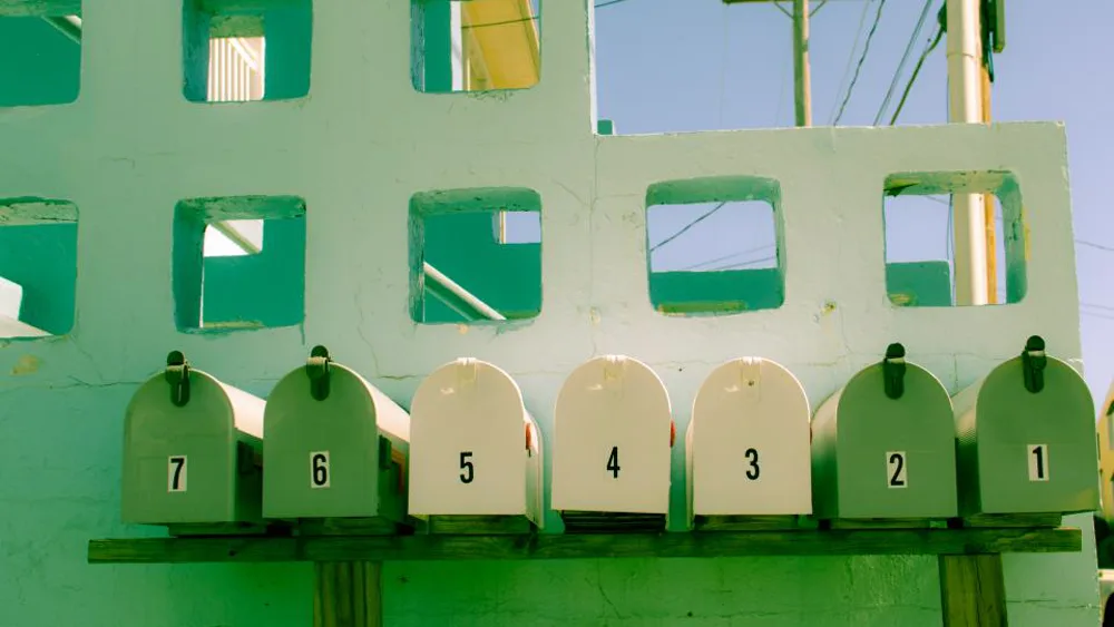 A row of numbered green and cream mailboxes