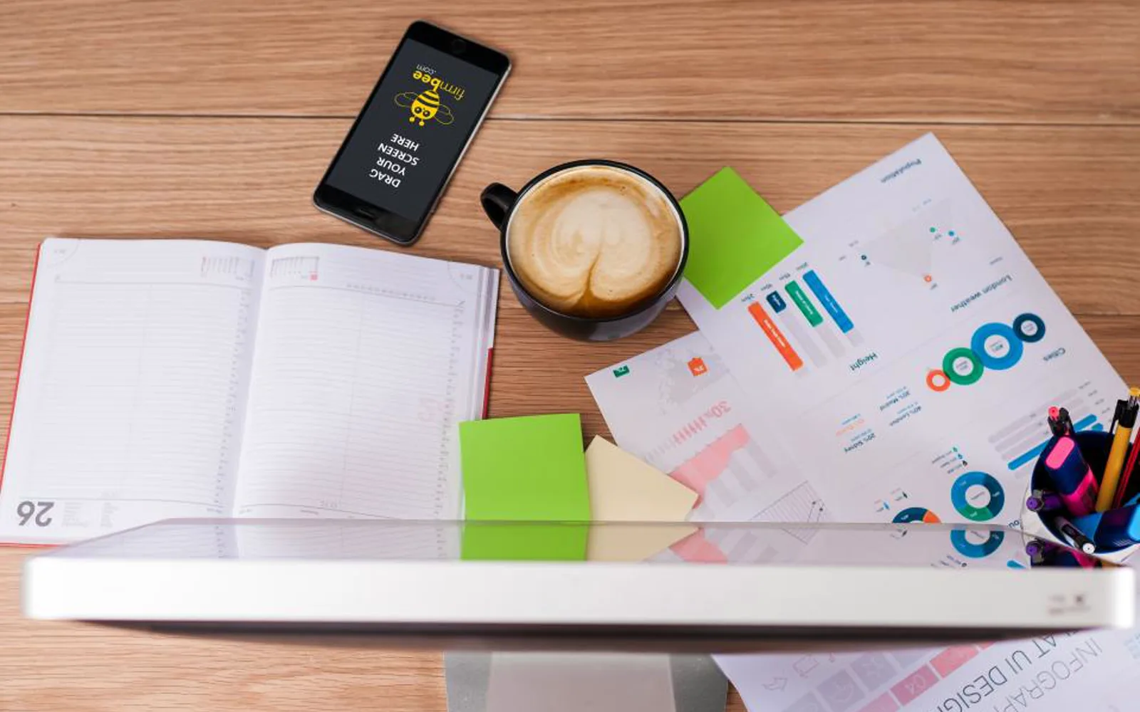 A desk with a notebook, phone and printed charts