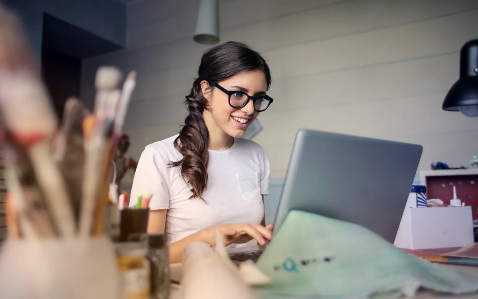 A smiling woman at a laptop in a bright studio